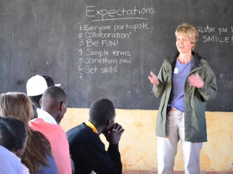 woman stands in front of chalk board speaking to crowd