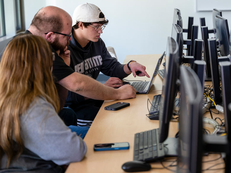Students working with a Professor on a computer
