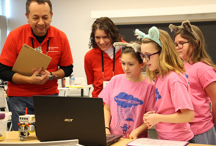Professors Flavio Cabrera and Dr. Marietta Scanlon listen to a team's presentation on their robot's programming