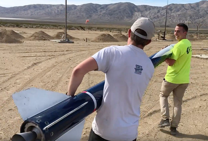 Two of the team members carry the rocket to the launch pad