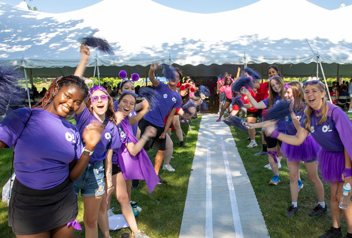 Students wearing bright colors cheer as they welcome new students.