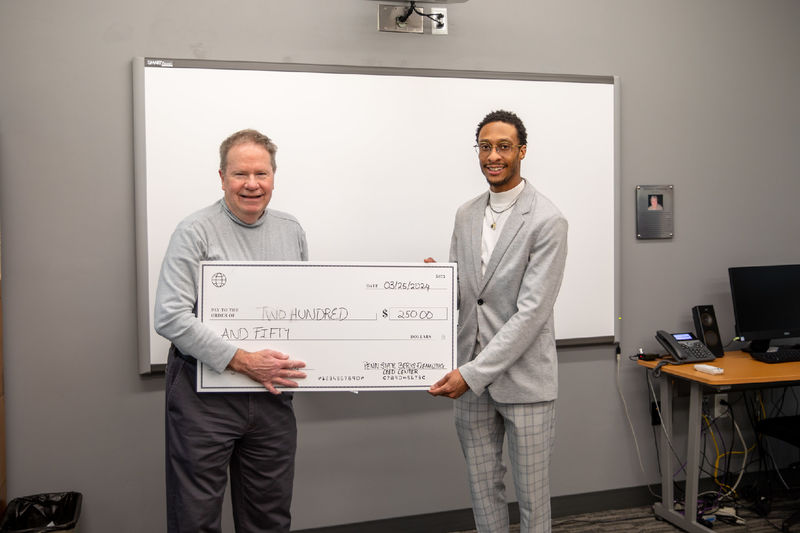 Male student poses with check of $250