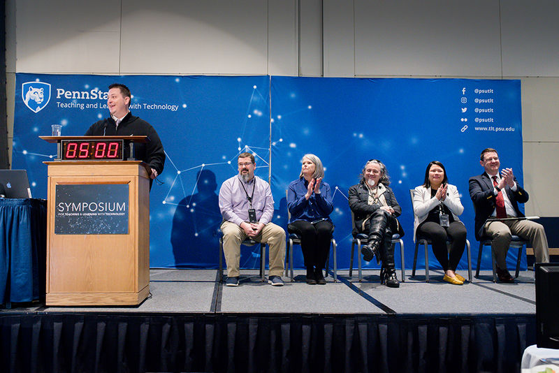 Five Open Innovation Challenge finalists are seated on stage as they wait to present their ideas