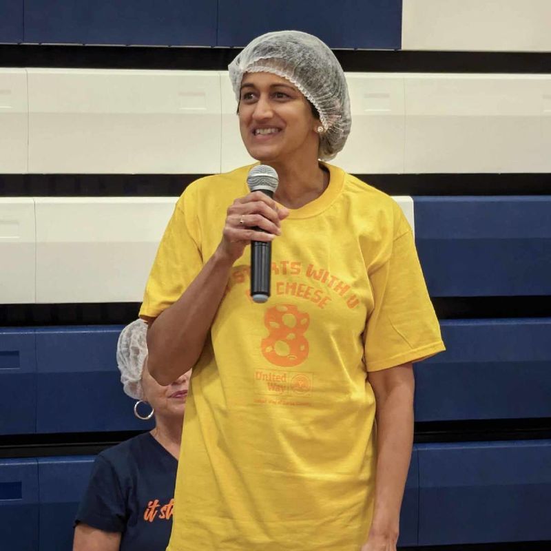 Pyati wearing hair net holding microphone speaking to crowd
