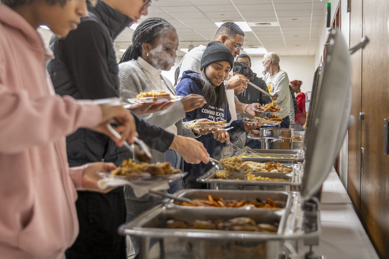 Students serve themselves food from chafing dishes.