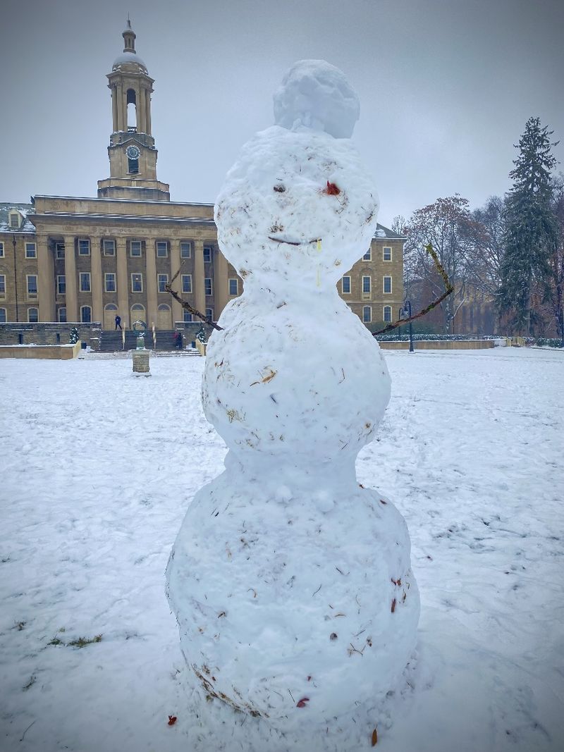 A snowman with Old Main in the background
