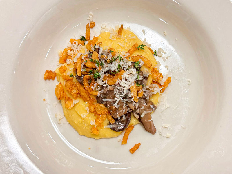Photograph of white plate with polenta, mushrooms, and fried onions with thyme