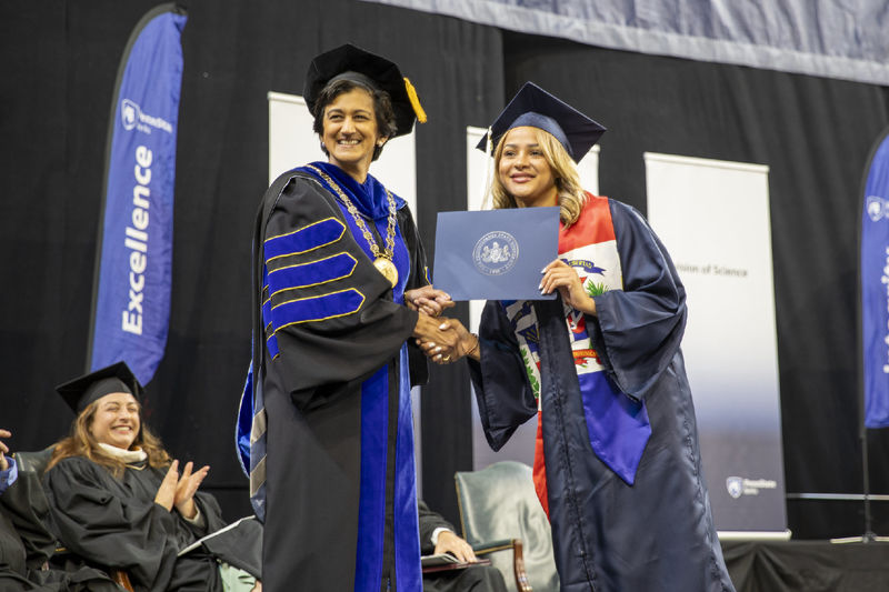 Chancellor Pyati poses with a graduate on stage