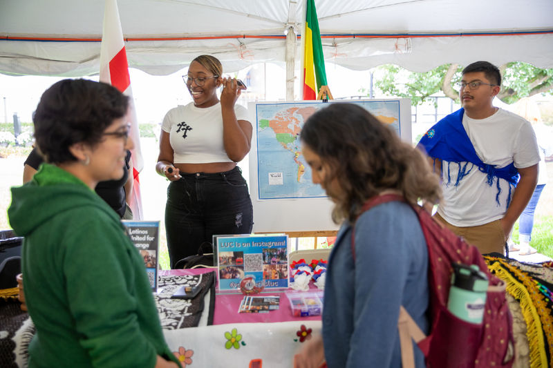 Two students learn about Latinos United for Change club while two students man the table