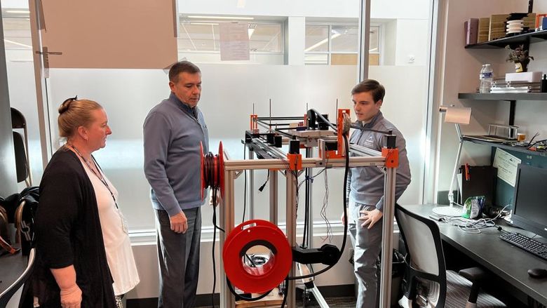Three people view technological prototype