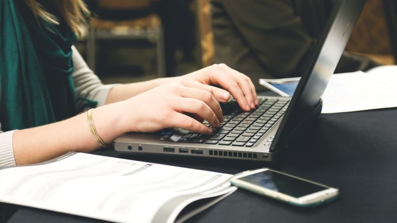A close-up photo of a woman typing on a computer