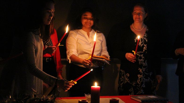 Students light a candle during the induction ceremony for Sigma Delta Pi