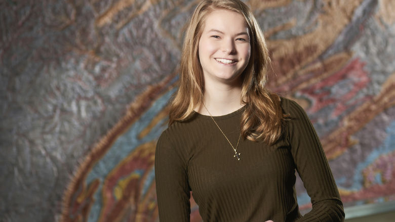 Sara Maholland standing in front of a topographical map of Pennsylvania