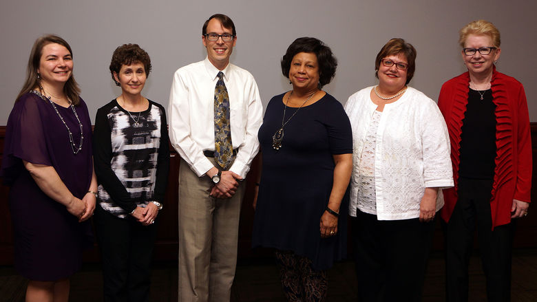 group of five women and one man standing in a row after being honored at a ceremony