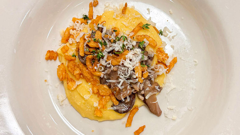 Photograph of white plate with polenta, mushrooms, and fried onions with thyme