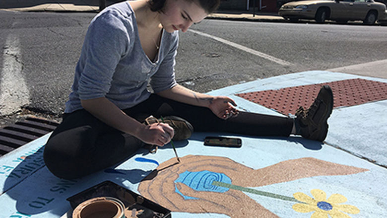 Berks student stencils "No Dumping, Drains to River" in Reading. 