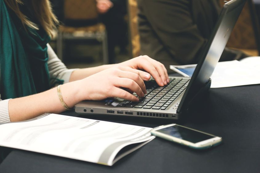 A close-up photo of a woman typing on a computer