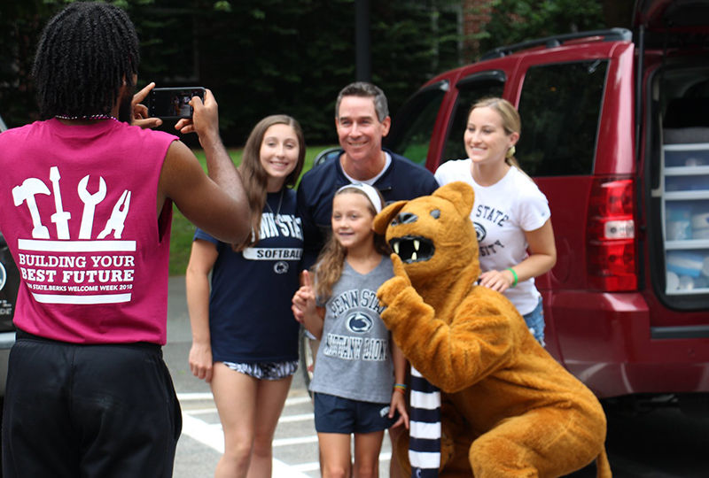 An orientation leader takes a family photo of a first year. An orientation leader takes a family photo of a first year.