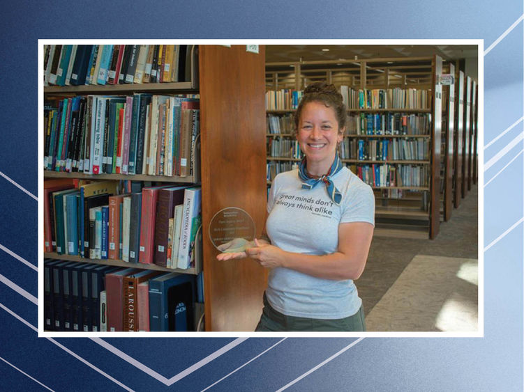 Person holding award in front of bookshelves
