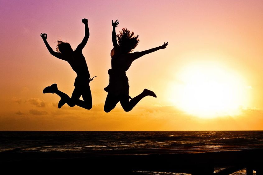 Two People Jumping In Front of a Sunset