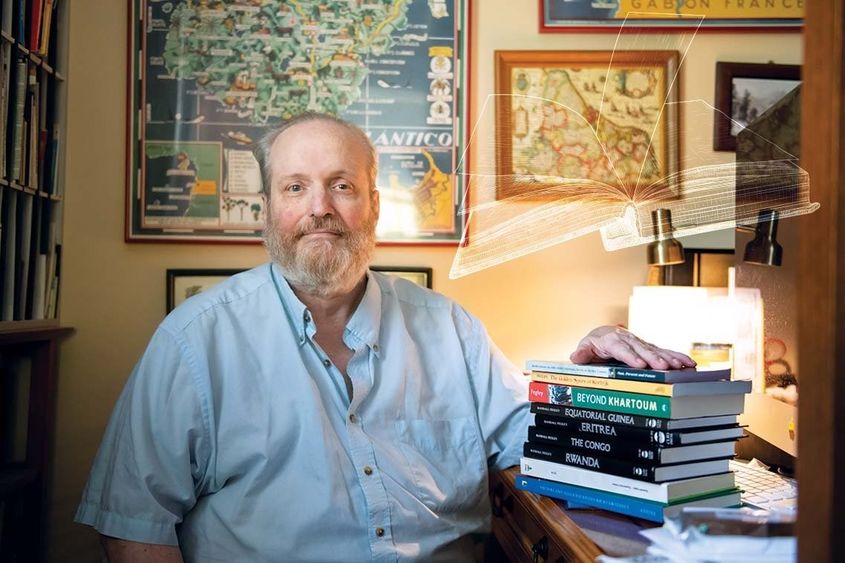 Randall Fegley sits at desk with books on top of it